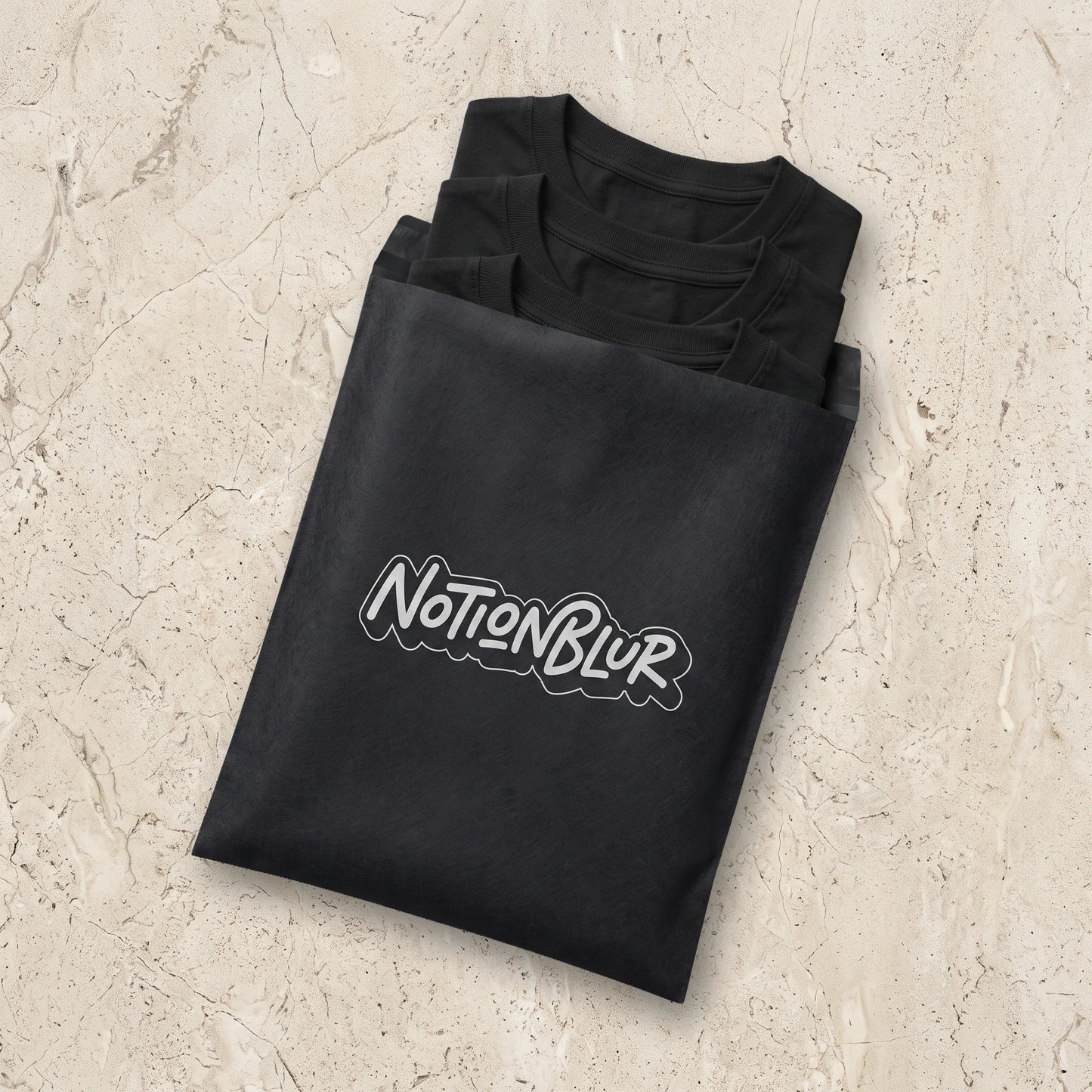 Three folded Notionblur tees in a black mailer on pale limestone