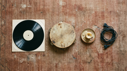 Overhead flat lay of a vinyl record in a blank sleeve, a tambourine, a candle stub and a coiled cable on a worn rug