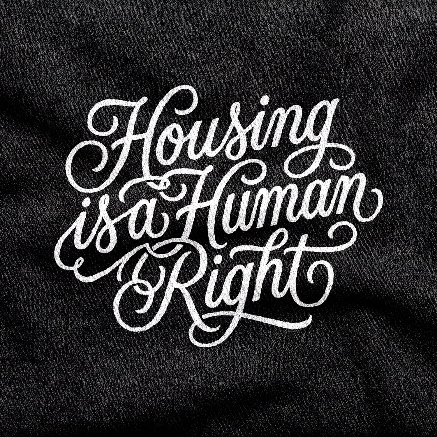 Housing is a Human Right design printed on a black cotton tee, close-up