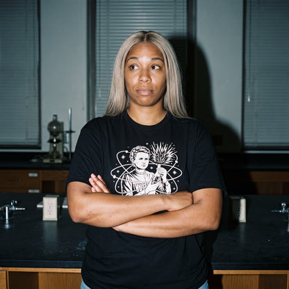 Woman wearing the Breaking Atoms Marie Curie black graphic tee