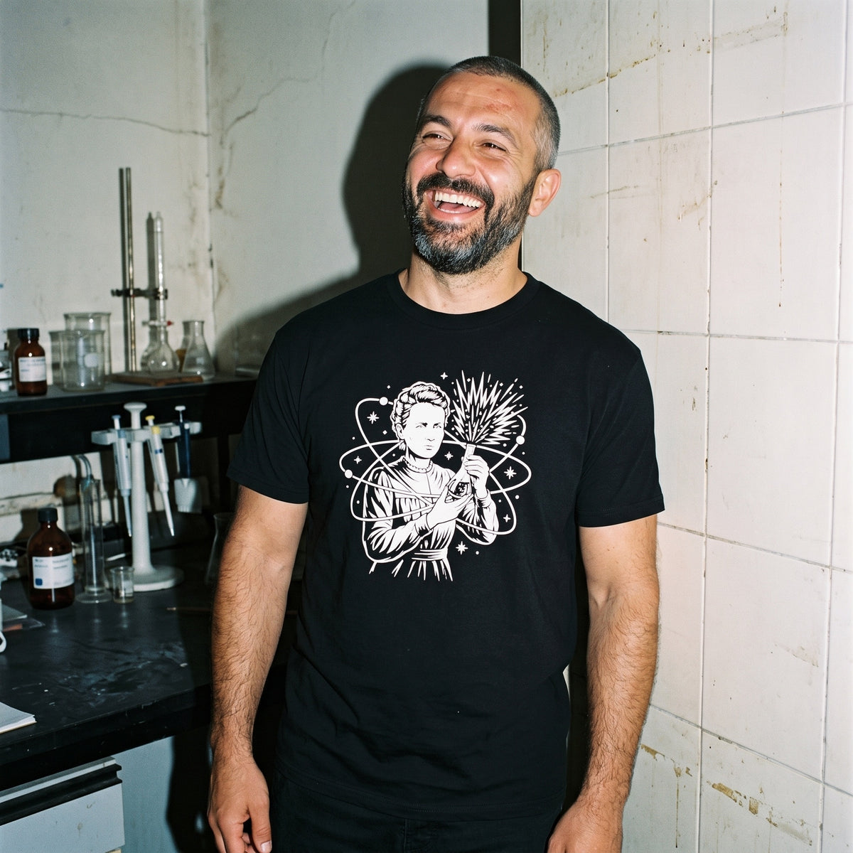 Man wearing the Breaking Atoms Marie Curie black graphic tee