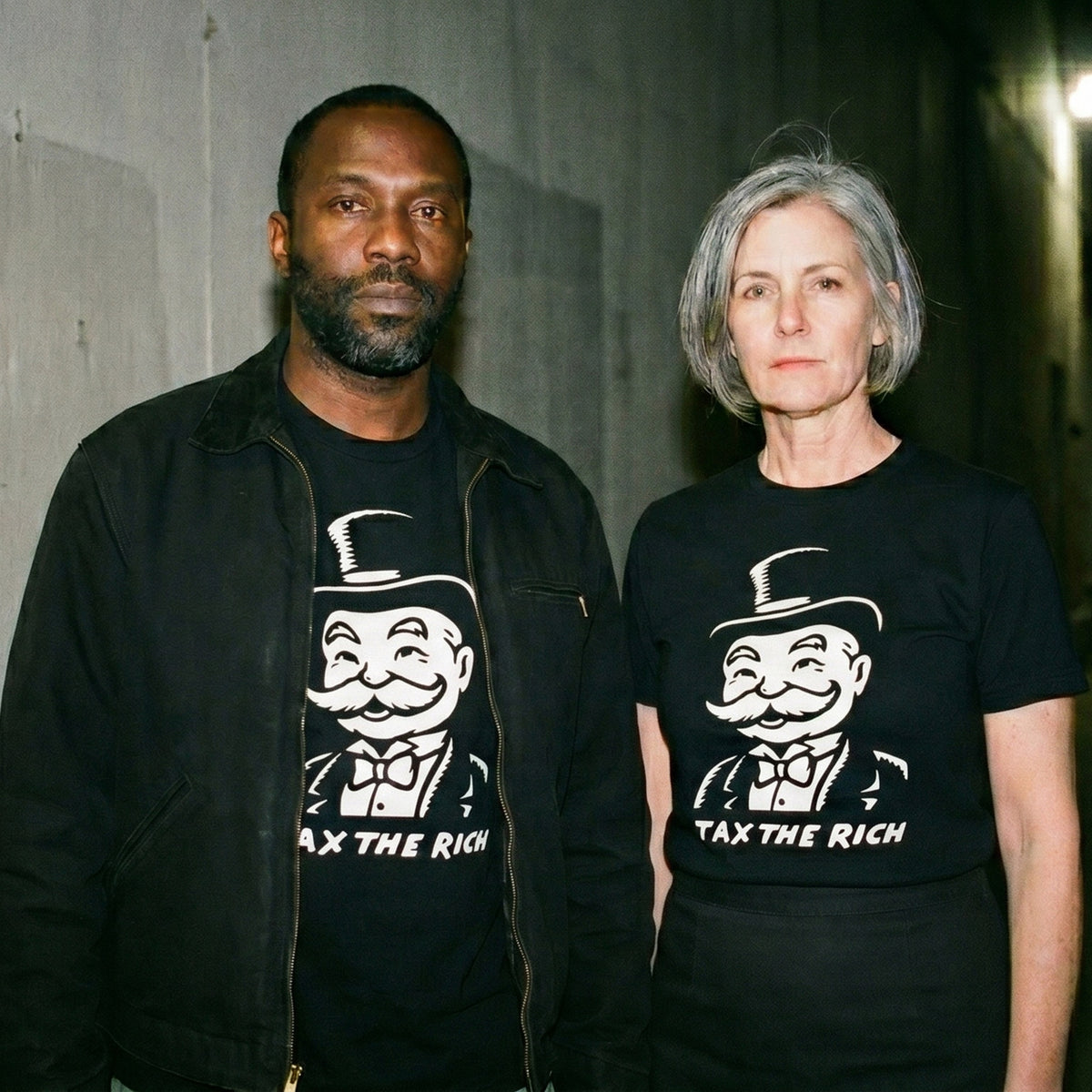 Two models wearing the Tax the Rich black graphic tee