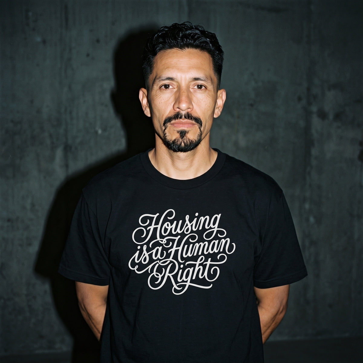 Man wearing the Housing is a Human Right black graphic tee
