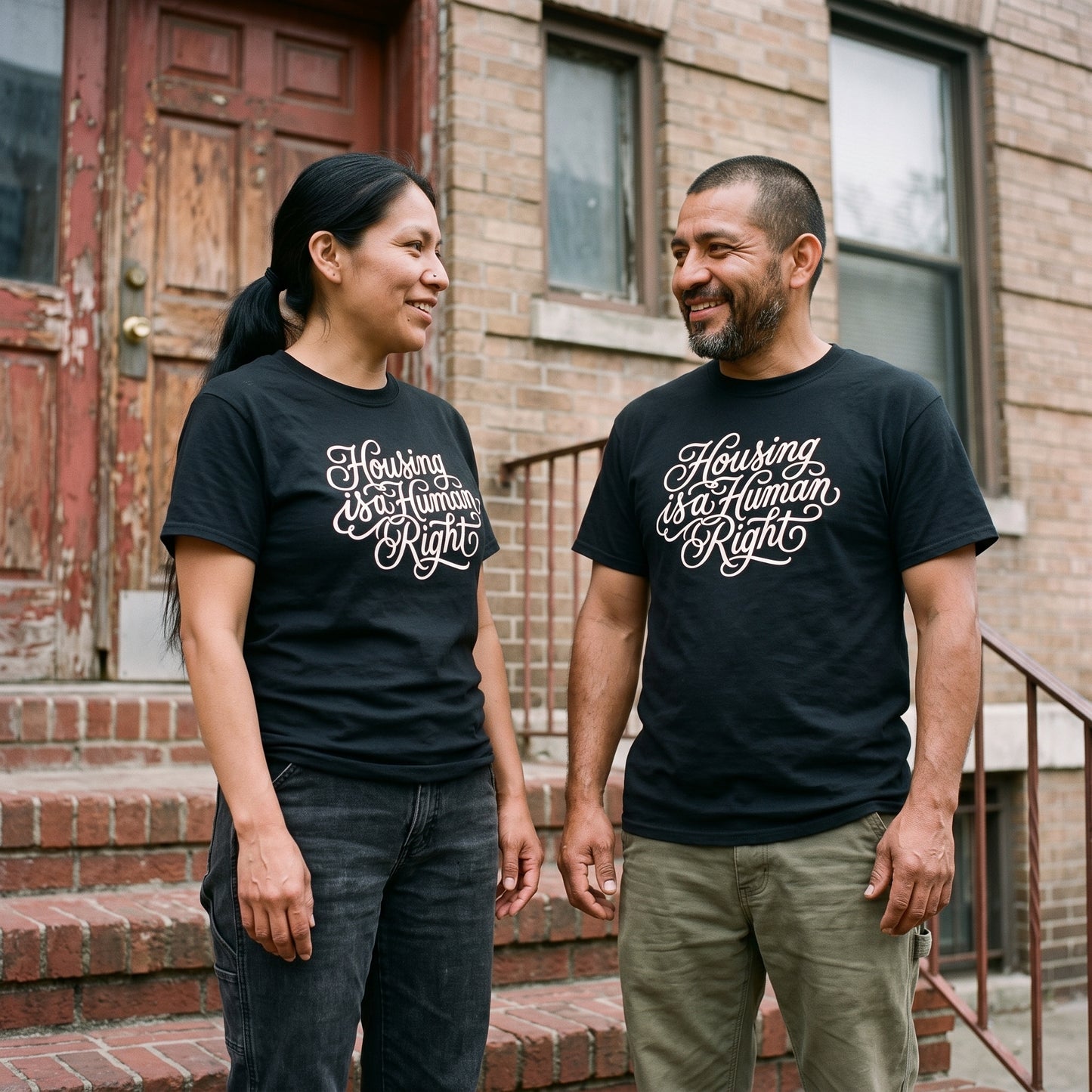 Two models wearing the Housing is a Human Right black graphic tee