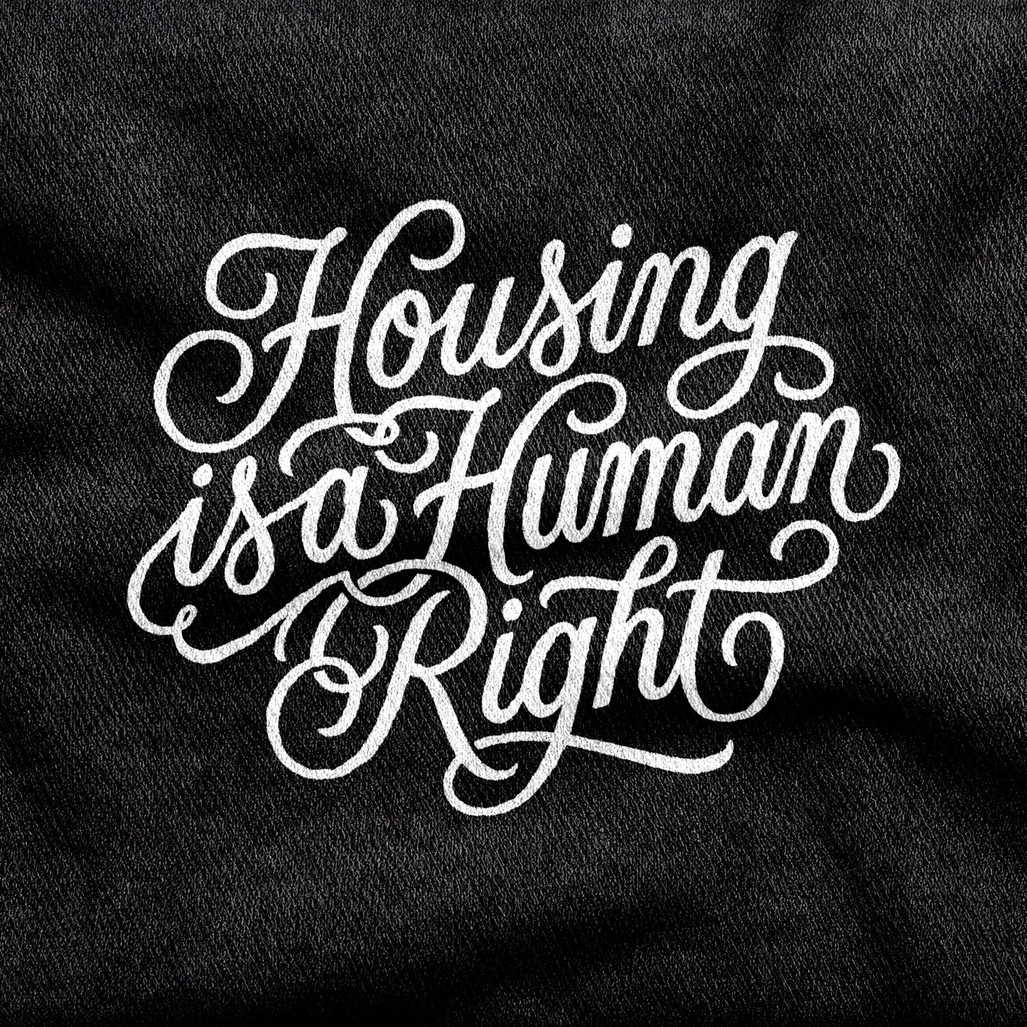 Housing is a Human Right design printed on a black cotton tee, close-up
