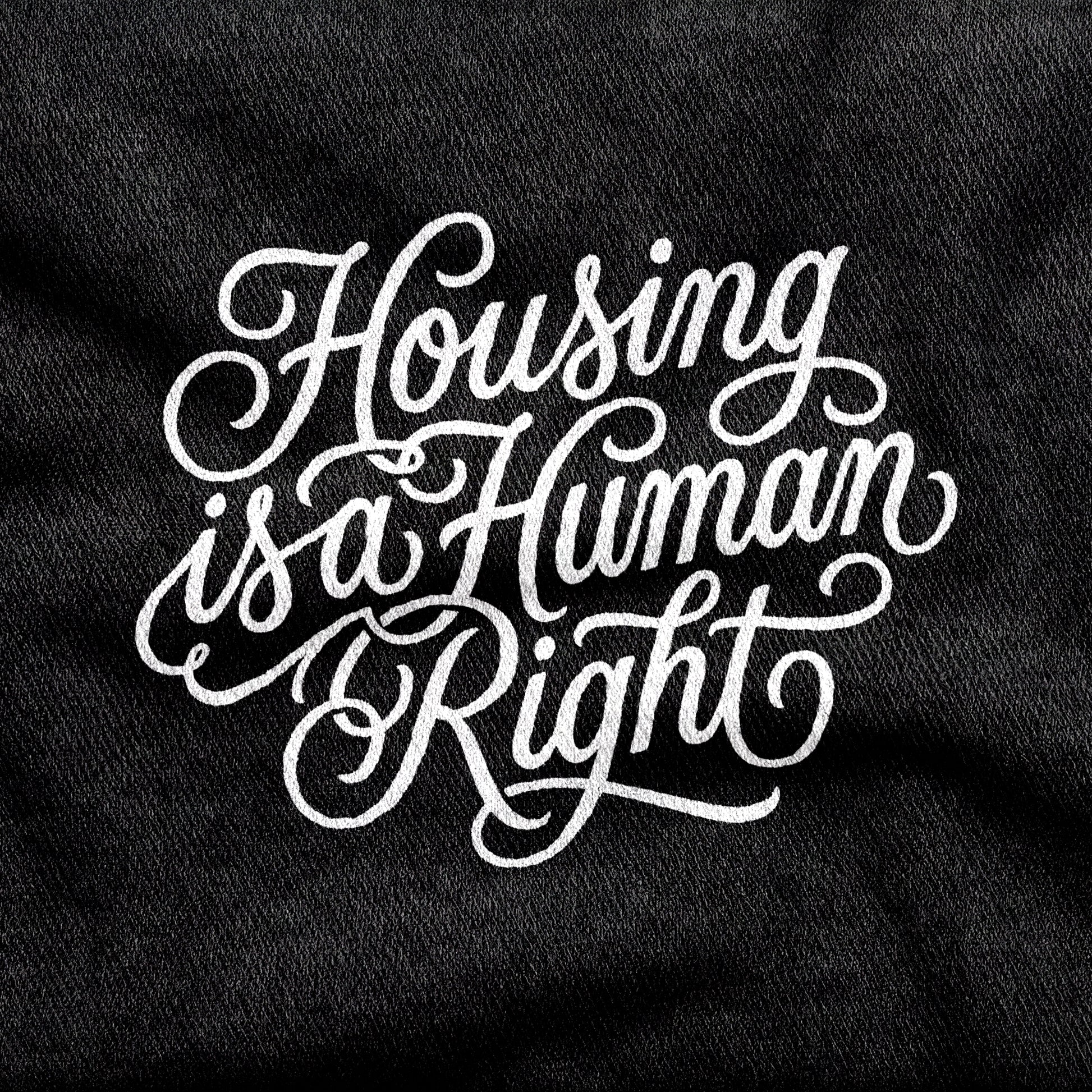 Housing is a Human Right design printed on a black cotton tee, close-up