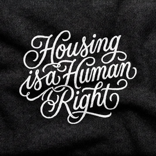 Housing is a Human Right design printed on a black cotton tee, close-up