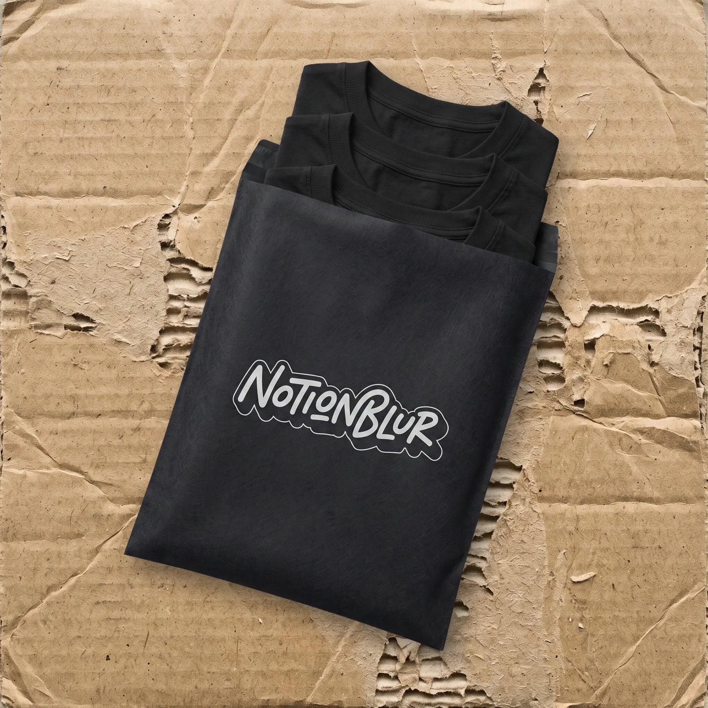 Three folded Notionblur tees in a black mailer on kraft cardboard